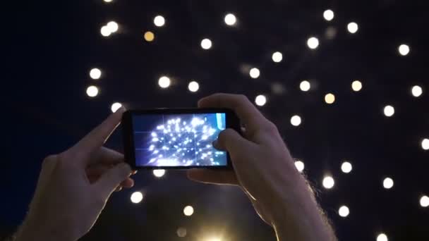 Manos del hombre tomando la foto a los fuegos artificiales con el nuevo teléfono inteligente — Vídeo de stock