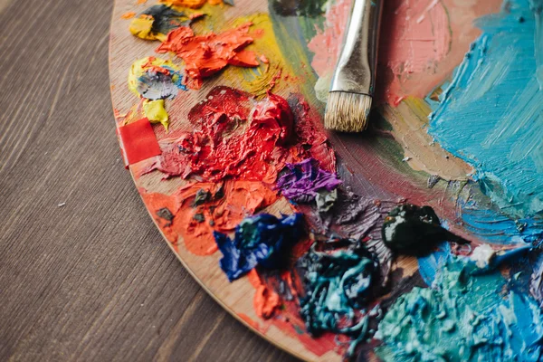 Mixes oil paints on palette with brush — Stock Photo, Image