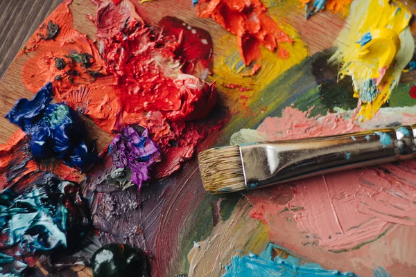 Mixes oil paints on palette with brush — Stock Photo, Image