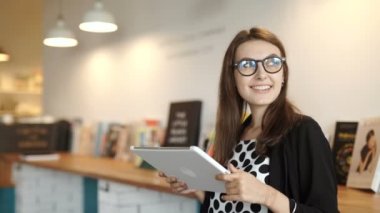 kadın bir restoranda bir masada oturur. Internet erişimi olan bir tablet taşıdı