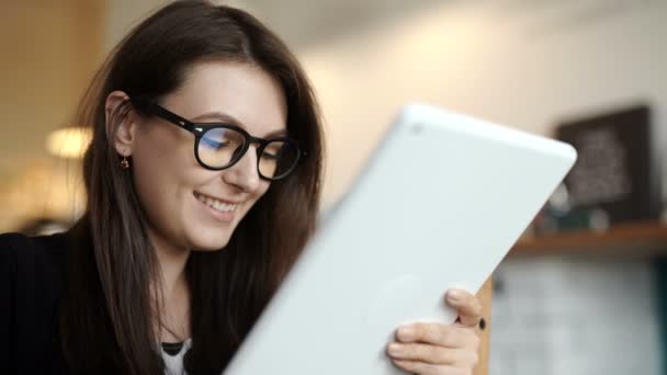 Vrouw zit aan een tafel in een restaurant. droeg een tablet met toegang tot Internet — Stockvideo