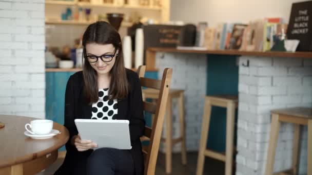 La mujer se sienta en una mesa en un restaurante. llevaba una tableta con acceso a Internet — Vídeos de Stock