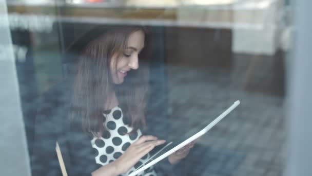 Jeune femme utilisant une tablette dans un café 