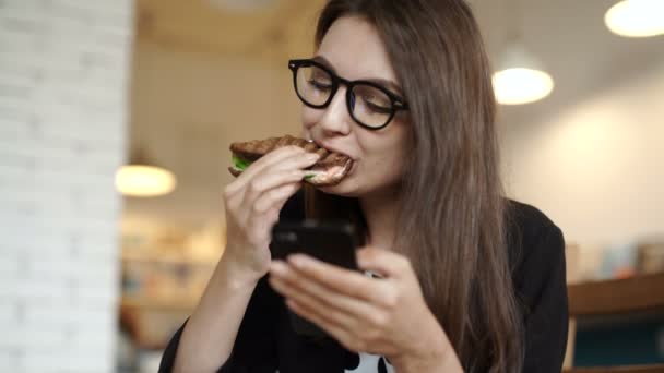 Кафе міського способу життя жінка по телефону їсть сендвіч — стокове відео