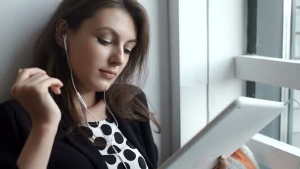 Jeune femme utilisant une tablette dans un café avec casque — Video