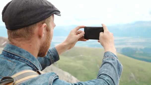 Turista tira fotos com telefone inteligente no pico do rock — Vídeo de Stock