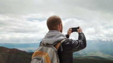 Güçlü adam uzun yürüyüşe çıkan kimse alarak fotoğraf dağ tepe, akıllı telefon ile. Muhteşem daybreak.