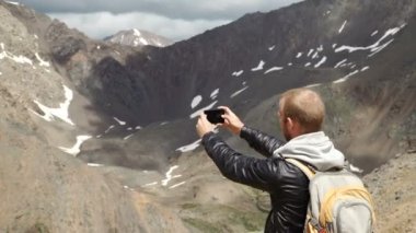 Turist akıllı telefon ile fotoğraf kaya tepe üzerinde alır.
