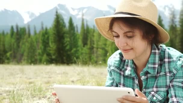 Giovane donna utilizzando tablet posa all'aperto su erba, sorridente — Video Stock