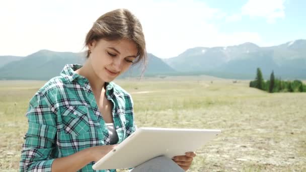 Hermosa chica marrón, en un páramo, utilizando una tableta de PC — Vídeo de stock