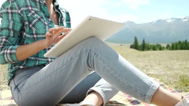 Jeune femme allongée sur l'herbe et utilisant une tablette — Video