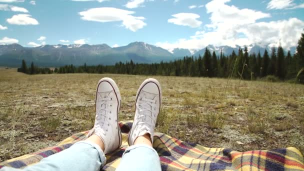 Piernas de viajero sentadas en una cima de alta montaña en viaje. Concepto de libertad — Vídeos de Stock