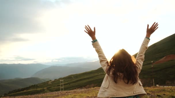 Glücklich jubelnde Siegerfrau bei Sonnenuntergang oder Sonnenaufgang mit erhobenen Armen über dem Kopf, um zu feiern, das Gipfelziel beim Wandern erreicht zu haben — Stockvideo