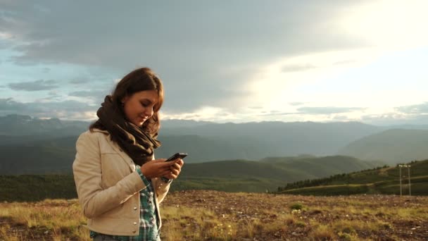 Kadın uzun yürüyüşe çıkan kimse günbatımı dağ tepe cliff cep telefonunu kullanma — Stok video