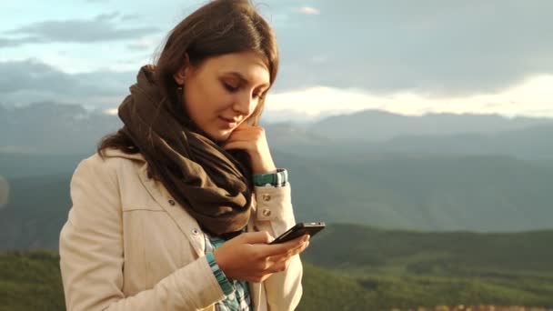 Mulher caminhante usar seu celular no pôr do sol montanha pico penhasco — Vídeo de Stock