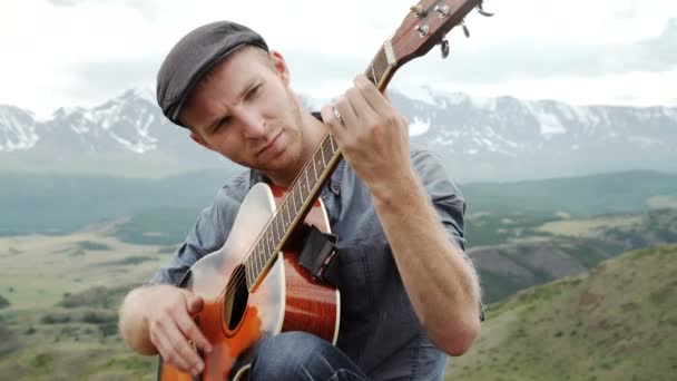 Young guy playing guitar sitting on the grass — Stock Video