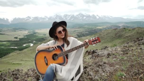 Frau mit ihrer Gitarre auf einem Felsen. — Stockvideo