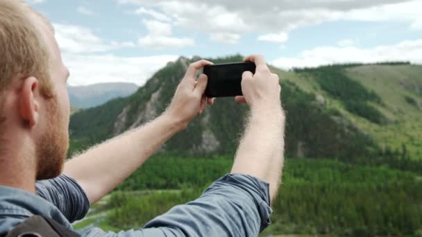 Hombre usando el teléfono inteligente tomar una foto vista de la montaña — Vídeos de Stock