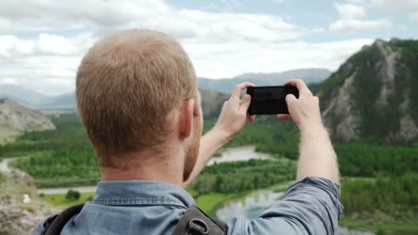 强壮的男人的徒步旅行者拍照智能手机在山的顶峰。奇妙的黎明. — 图库视频影像