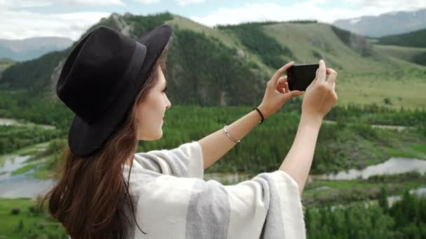 Mulher caminhante tirar foto com telefone inteligente no penhasco pico da montanha — Vídeo de Stock