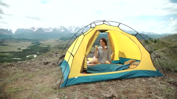 A woman on her phone while in her tent and sleeping bag — Stock Video