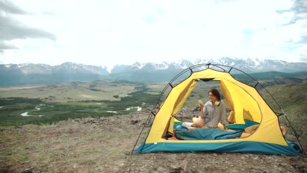 Young woman listening to an mp3 player in a tent — Stock Video