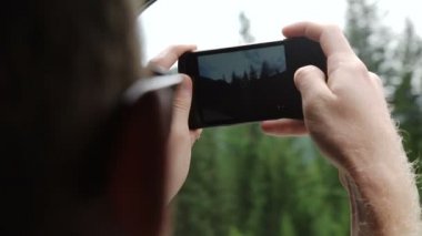 Arkadan görünüşü genç çift araba ve yol ile smartphone fotoğraflarını alarak sürüş