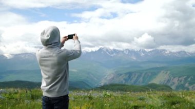 Güçlü adam uzun yürüyüşe çıkan kimse alarak fotoğraf dağ tepe, akıllı telefon ile. Muhteşem daybreak.