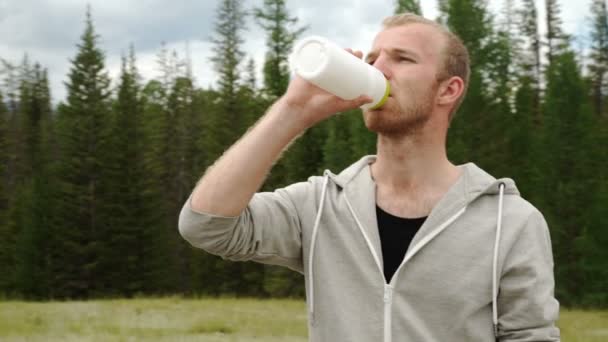 Jonge gespierde bouwen man drinkwater van fles na het lopen, — Stockvideo