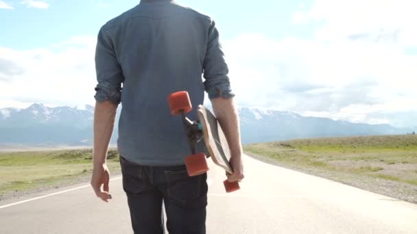 Sport, tempo libero, persone e concetto di adolescente - giovane o adolescente sorridente con longboard sulla strada di montagna . — Video Stock