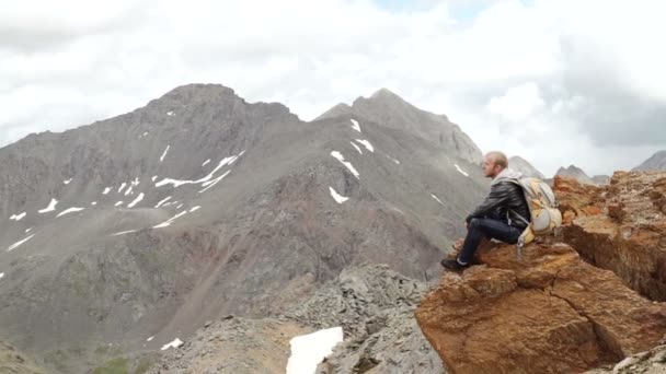 Hombre en la cima de la montaña sentado en la roca viendo un bonito amanecer en el pueblo . — Vídeos de Stock