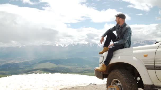 Ευτυχισμένος ταξιδιώτης άνθρωπος κάθεται στο αυτοκίνητό του πάνω σε βουνά. 4 x 4 ταξίδια πεζοπορίας — Αρχείο Βίντεο