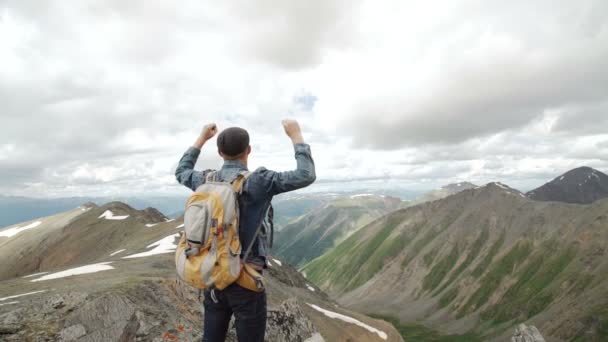 Vandrer med ryggsekk på toppen av et fjell med hevede hender og soloppgang – stockvideo