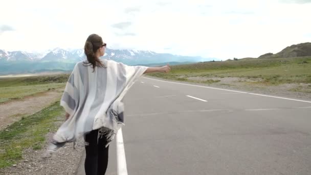 Jonge vrouw liften op een weg op de velden — Stockvideo