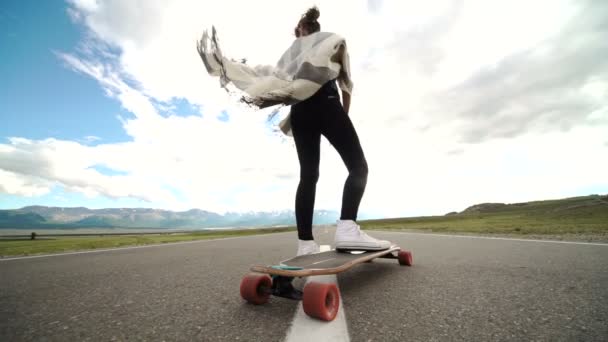 Jonge vrouw met schaatsen board op blauwe hemelachtergrond — Stockvideo