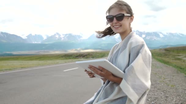 Красивая женщина сидит на чемоданах на пустынной дороге — стоковое видео
