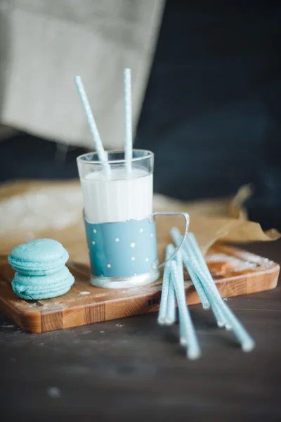 Синій келих молока з французькими макарунами на дерев'яній дошці — стокове фото