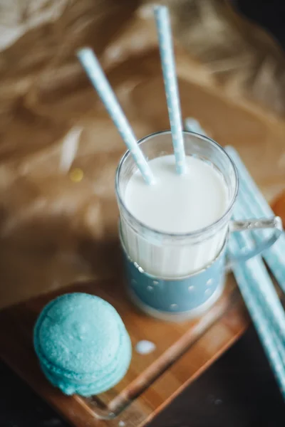 Verre bleu de lait avec macaron français sur planche de bois — Photo