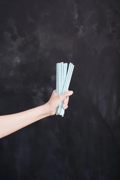 Woman hand hold cocktail straw blue on black background — Stock Photo, Image