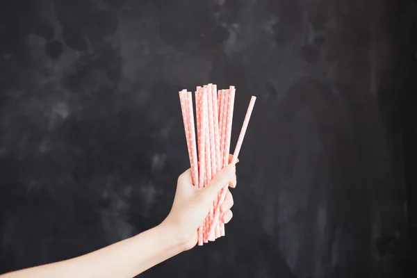 Woman hand hold cocktail straw on black background — Stock Photo, Image
