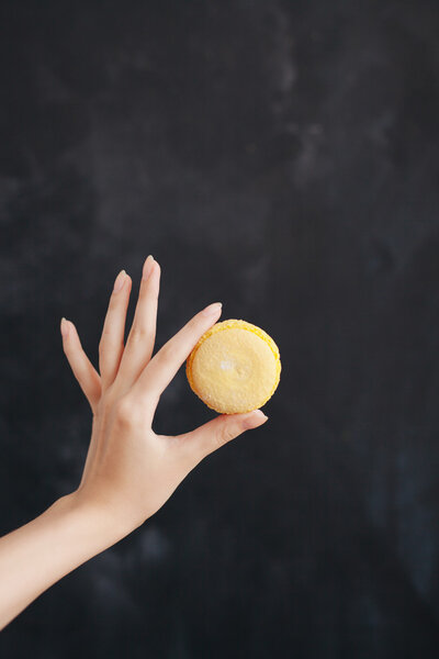 Yellow macaroon almond cake in a womans hand
