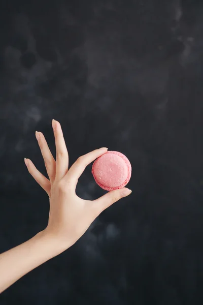 Macaron rose gâteau aux amandes dans une main de femme — Photo