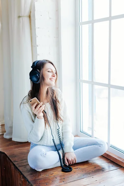 Mulher ouvir música em fones de ouvido no fundo do parapeito da janela — Fotografia de Stock