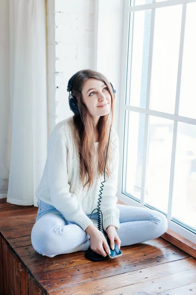 Mulher ouvir música em fones de ouvido no fundo do parapeito da janela — Fotografia de Stock