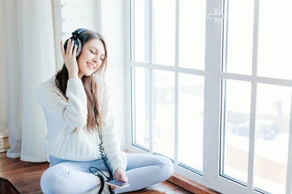 Mulher ouvir música em fones de ouvido no fundo do parapeito da janela — Fotografia de Stock