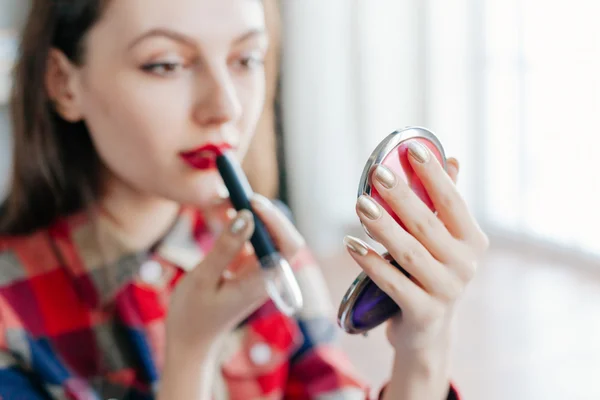 Bela jovem mulher aplicando sua maquiagem no espelho — Fotografia de Stock