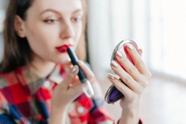 beautiful young woman applying her make-up in the mirror