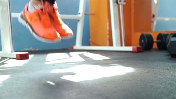 Eine Frau in sportorangefarbenem Outfit springt in der Turnhalle über das Seil. 1080p Zeitlupe — Stockvideo