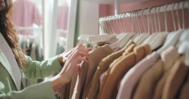 Giyim mağazası. Kadın kıyafetleri mağazanın içindeki askılara asılı. Alıcılar Seçer. Butik. Yakın plan. Alışverişe. Çeşitli Tarzlarda Bir Çok Kıyafet. Elbiseler, ceketler, gömlekler, etekler ve diğer şeyler.
