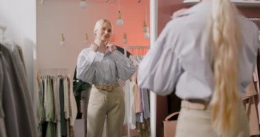Bir Sarışın Kadın Alıcının Bir Giysi Dükkanında Görünüşü Aynanın Önünde Duruyor ve Bir Clothers Deniyor